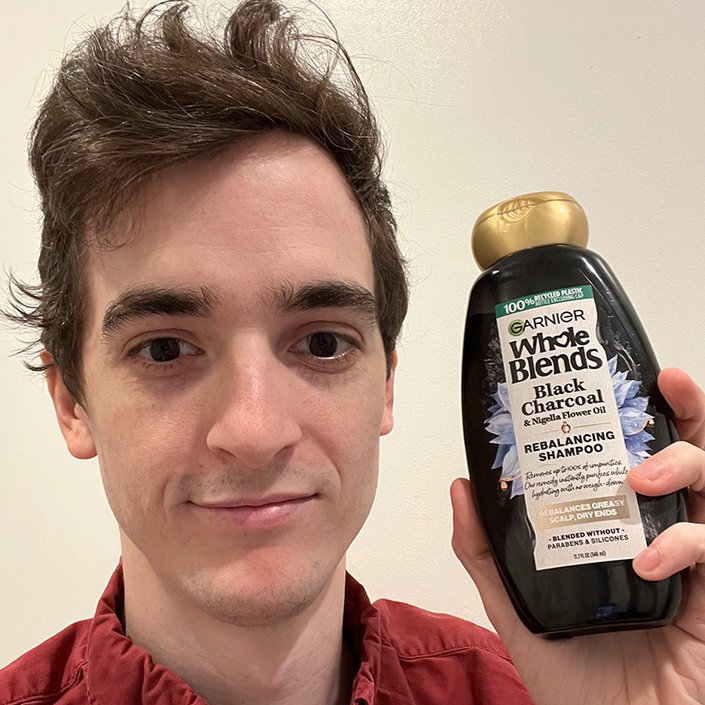 stephen holding the Garnier Whole Blends Black Charcoal and Nigella Flower Oil Shampoo