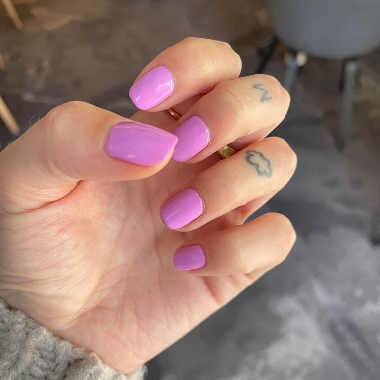 Photo of editor's hand with pink-purple nail polish