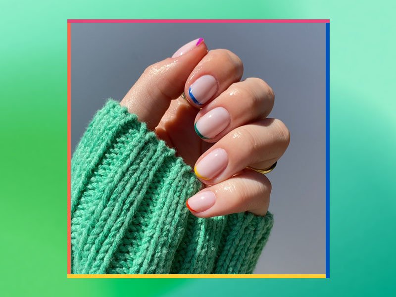 person wearing a green sweater sleeve showing off their micro french nail art