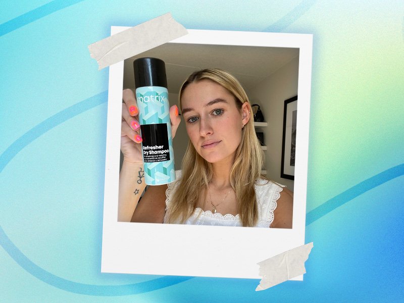 Editor with long blonde hair holds up a bottle of Matrix Refresher Dry Shampoo
