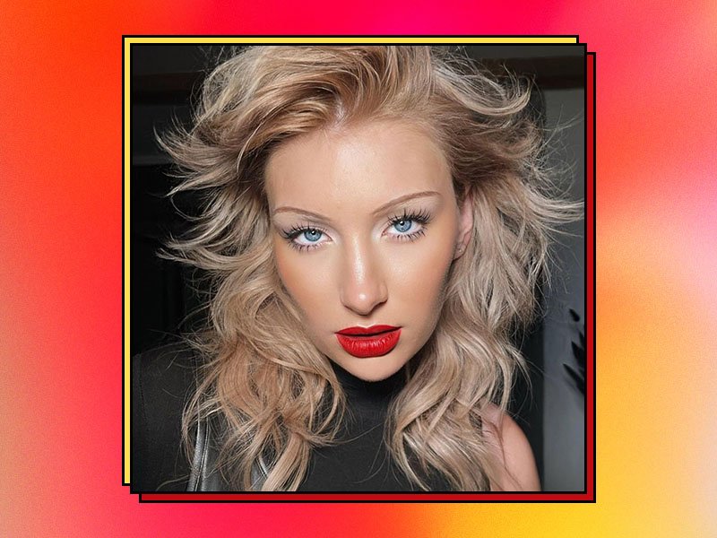 Picture of a blonde model with thin brows and red lipstick, on a red and orange graphic background