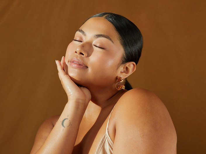 person touching face with dewy makeup on