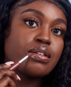 Close-up picture of a black model applying nude lip gloss