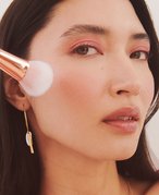 person applying blush to the apple of their cheek