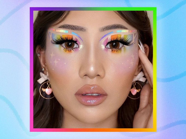 Picture of a model with colorful rainbow-and-star makeup, with a graphic rainbow background
