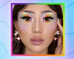 Picture of a model with colorful rainbow-and-star makeup, with a graphic rainbow background