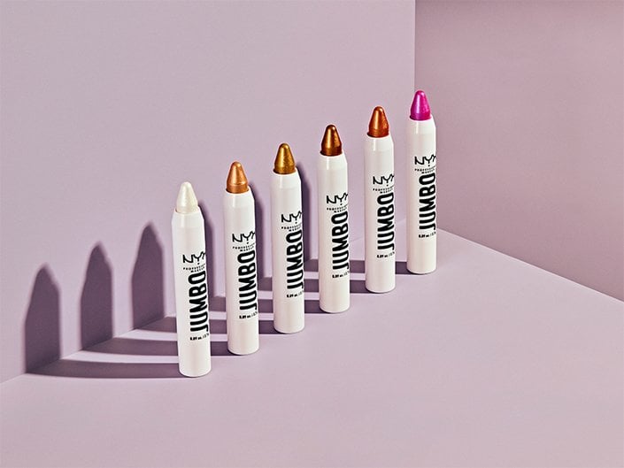 A picture of the NYX Professional Makeup Jumbo Multi-Use Highlighter Sticks lined up on a pink background