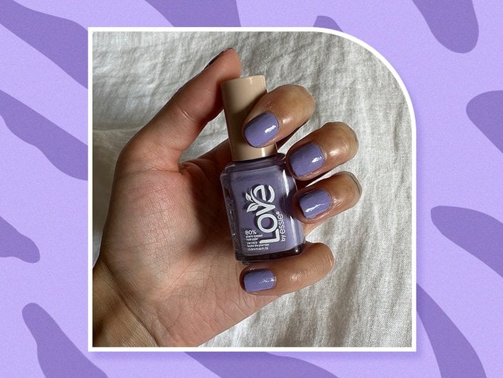Hand with nails painted purple holding a bottle of the LOVe by Essie Nail Polish in the shade Playing in Paradise, collaged on a purple background