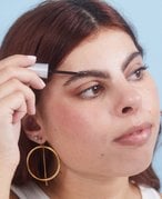 Picture of a person looking to the side while applying eyebrow gel