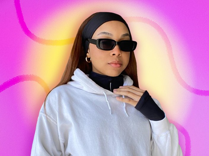 Photo of a person with long dark hair styled with a black stretchy headband, wearing a white hoodie and black sunglasses, collaged on a pink and yellow tie-dye background