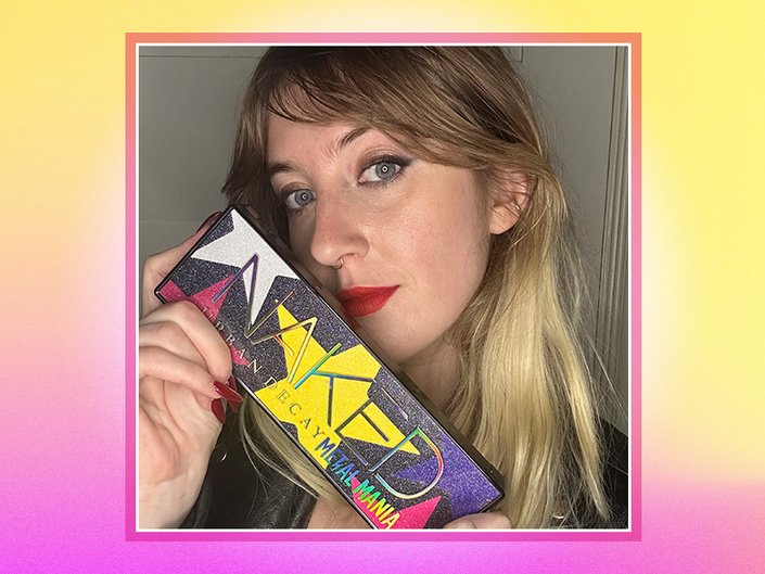 Picture of the editor holding the Urban Decay Naked Metal Mania Eyeshadow Palette on a pink and yellow gradient graphic background