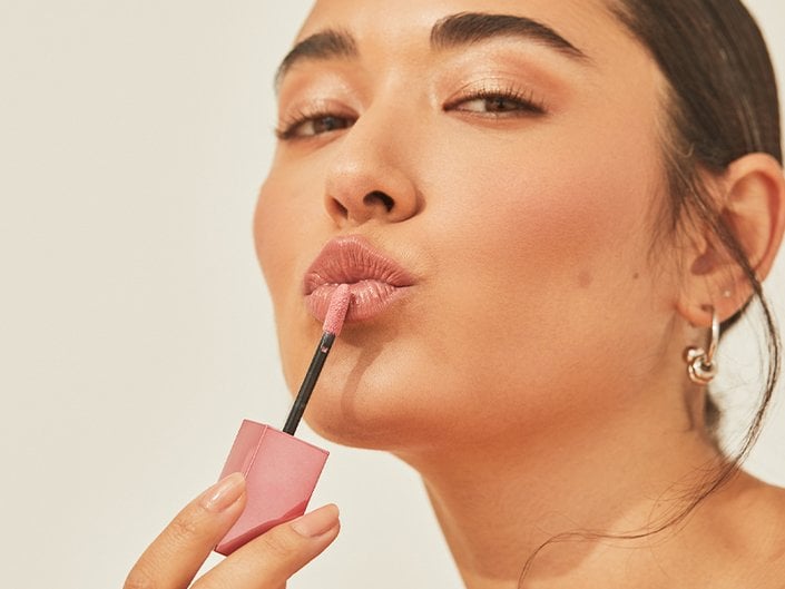 Person applying lip gloss to their lips