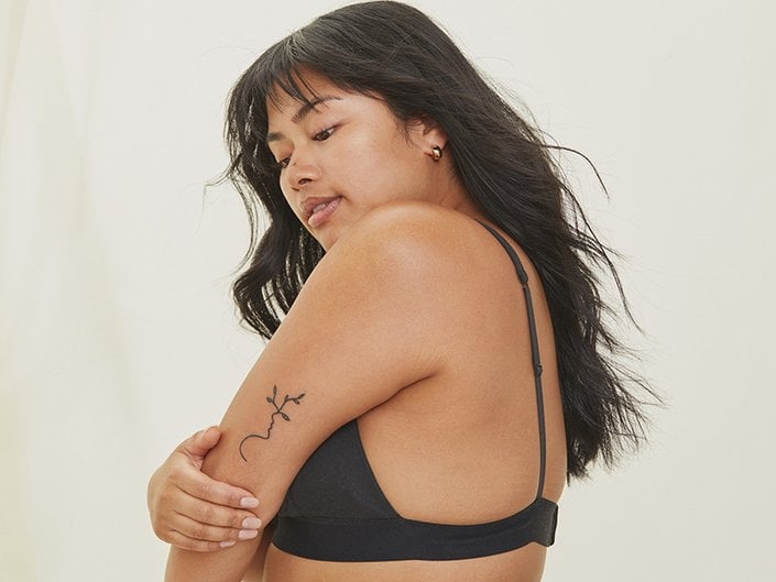 Picture of a person with long dark hair and a tattoo on their arm