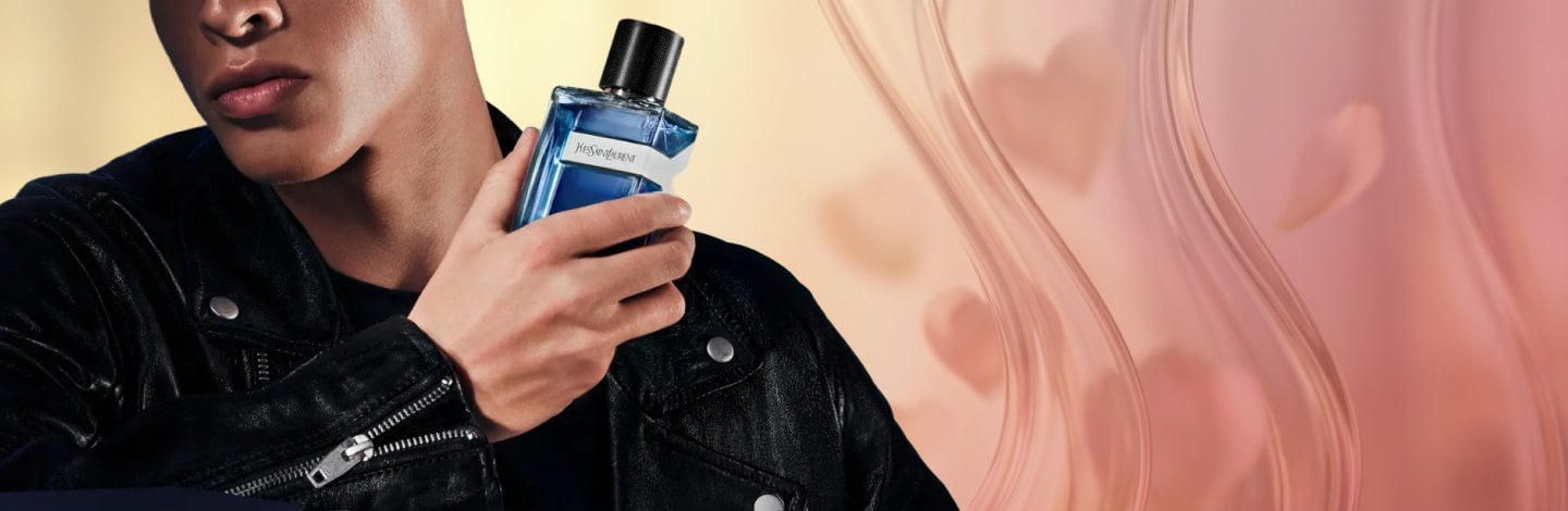 Man holding a bottle of Yves Saint Laurent cologne on a textured background