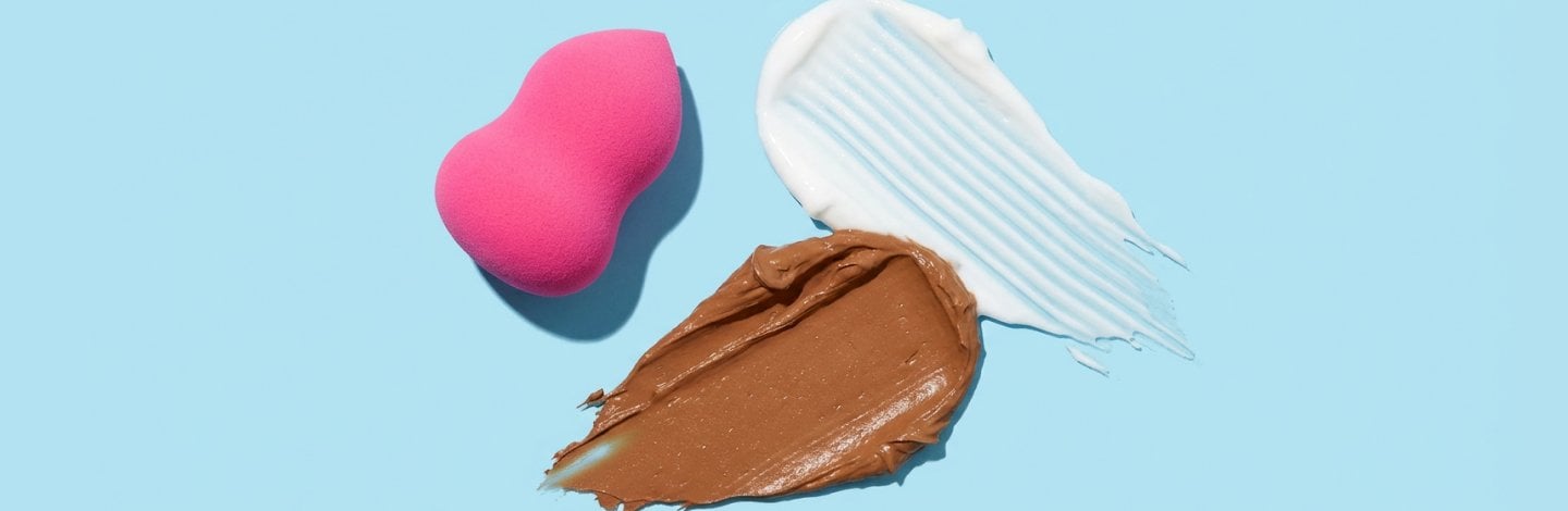 Foundation and moisturizer swatch next to a beauty blender tool against a blue background