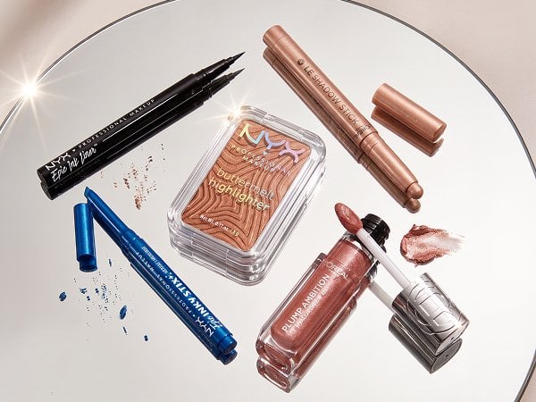 Stacked arrangement of featured glitter makeup products with sparkling packaging on a mirrored surface, evoking a show-stopping, radiant sparkle theme.