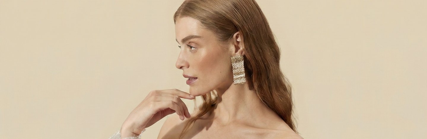 Makeup Woman’s side profile, wearing large gold earrings, an off the shoulder top, who has glowing skin