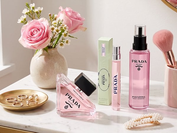 An image featuring Prada Paradoxe Virtual Flower Eau de Parfum, Prada Infusion de Rose, and Prada Paradoxe Sweet Chemistry displayed on a pretty vanity — maybe with a vase of flowers, jewelry, hair clip, ring dish, makeup brush, etc.  