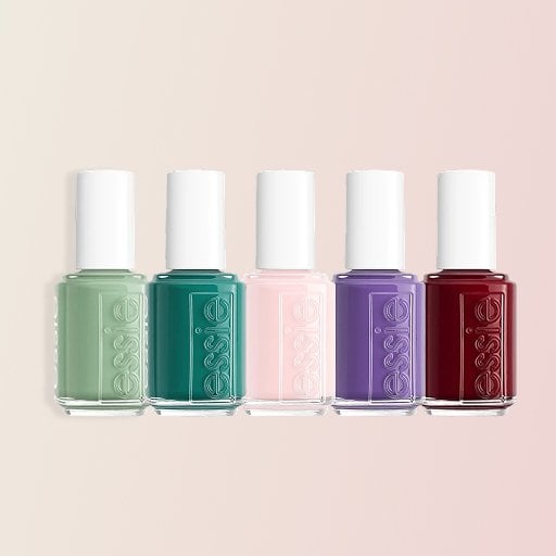 Five bottles of Essie Nail Polish in the shades Berry Naughty, (Un)Guilty Pleasures, Wink of Sleep, Ballet Slippers, and Crunch Crunch on a pink background