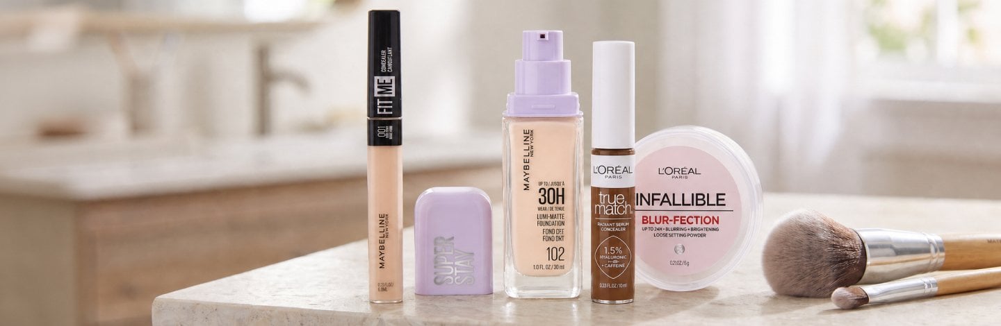 Image of concealers mentioned in this article, arranged on a countertop along with a couple makeup brushes: Maybelline New York Fit Me Concealer, Maybelline New York Super Stay Lumi-Matte Foundation, L’Oréal Paris Infallible Blur-fection Longwear Loose Setting Powder