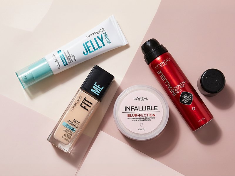 Branded flat lay of the featured products (Maybelline Poreless Jelly Hydrating Blur Primer, Maybelline Fit Me Matte + Poreless Foundation, L'Oréal Paris Infallible Blur-Fection Longwear Loose Setting Powder, L'Oréal Paris Infallible 3-Second Setting Mist). Arrange on a matte background with subtle shine and shadow play to evoke the oil-control theme. Lean into geometric or brand color backgrounds for energy.