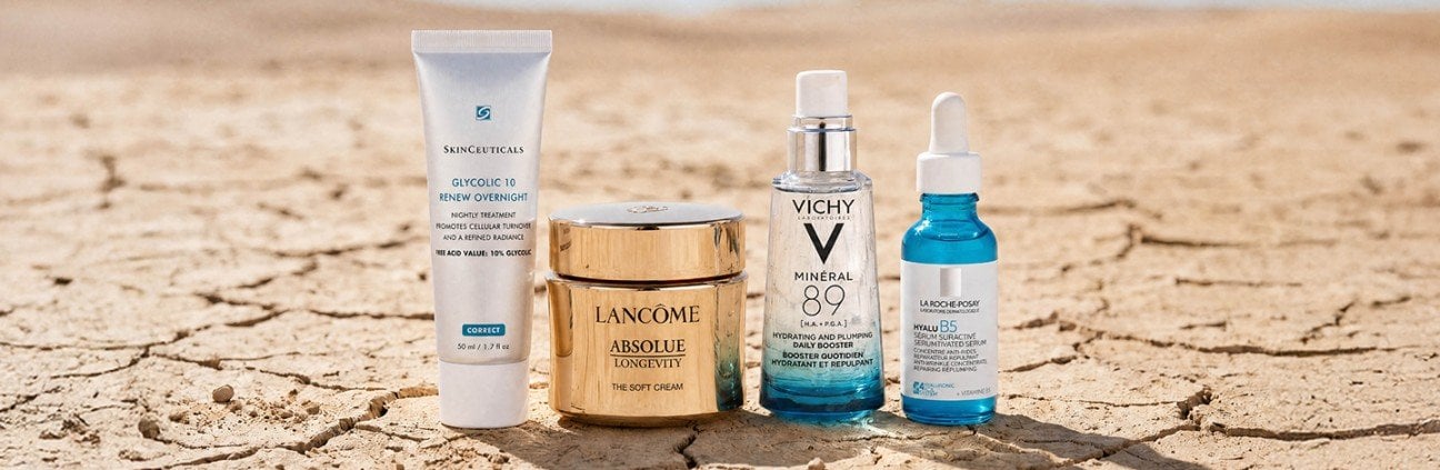 Image of SkinCeuticals, Lancome, Vichy, La Roche-Posay products on a beige cracked ground gradient background